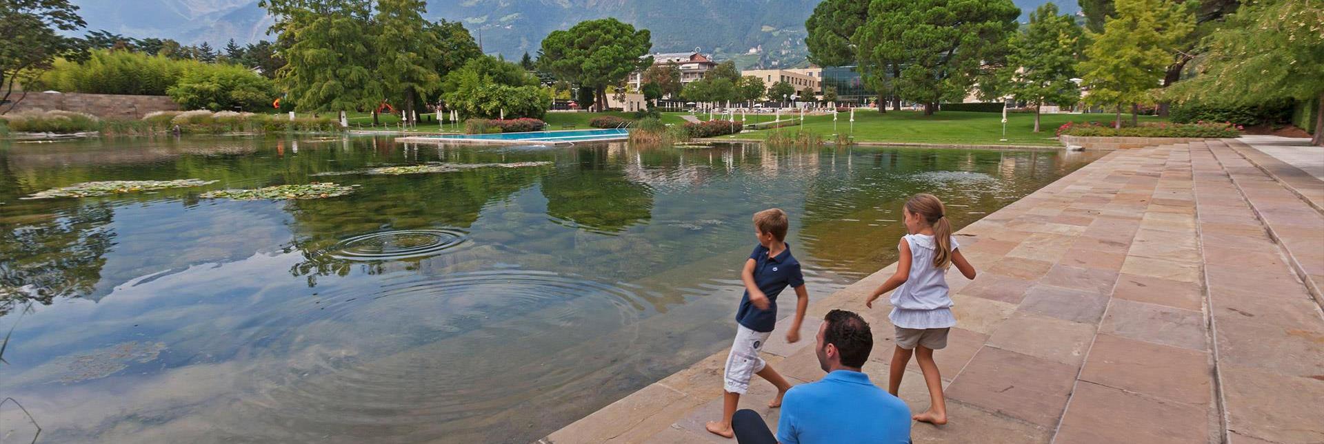 Kinder werfen Steine ins Wasser eines Teichs