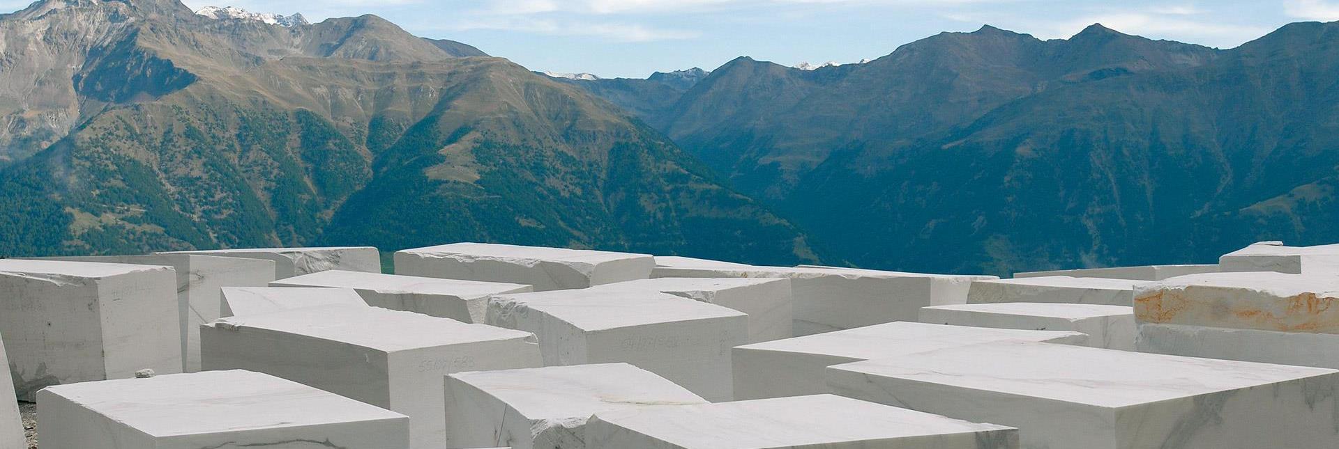 Blocchi di marmo bianco su un altopiano montano con vista sulle Dolomiti